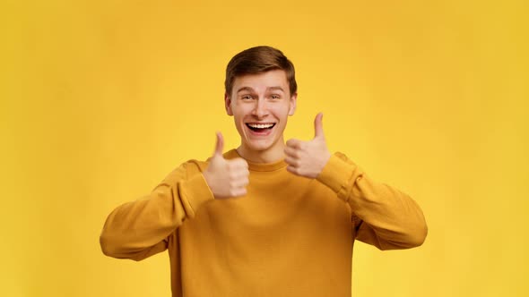 Man Gesturing Thumbs Up With Both Hands Over Yellow Background