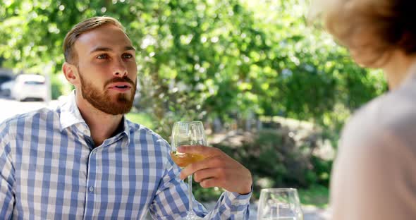 Man interacting with female friend while having wine