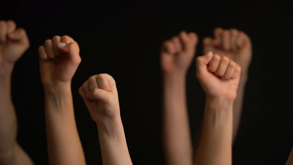 Raising Hands with Fists on Black Background