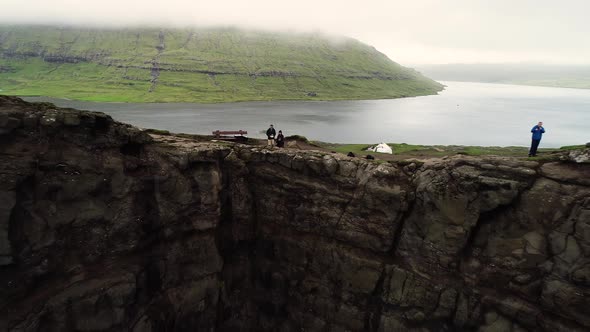 Aerial view of couple standing on the edge of foggy English Slave cliff.