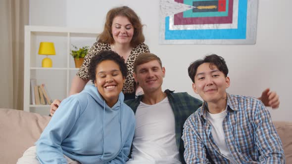 Happy Diverse Friends Relaxing on Comfortable Couch in Apartment Enjoying Leisure Time