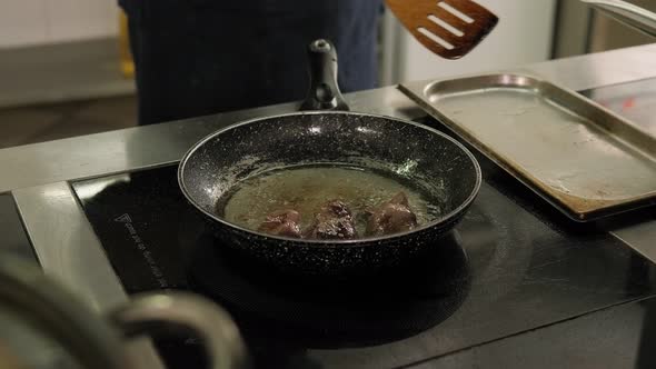 Closeup of a Cook Fries a Chicken Liver in a Pan in the Kitchen