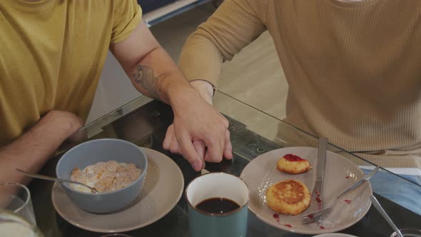 Unrecognizable Men Holding Hands during Breakfast