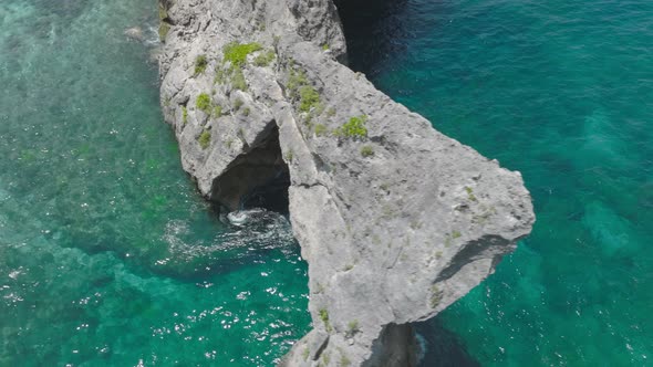 Cinematic shot of famous rock arch on Nusa Batupadasan at Atuh Beach, aerial