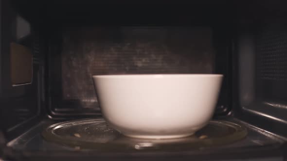 African Woman Reheat Food in Ceramic Bowl Using Microwave Oven