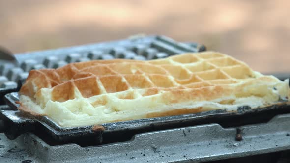 Close Shot of a Waffle Iron Being Opened with the Waffle Being Red with Tongs