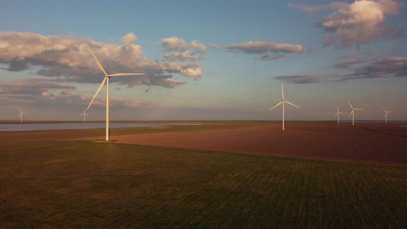 Aerial View of Wind Turbines and Agriculture Field Near the Sea at Sunset