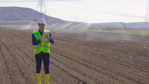 Engineer works with tablet in farmland.