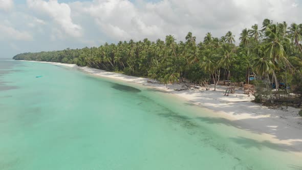 Aerial: woman relaxing on white sand beach turquoise water tropical