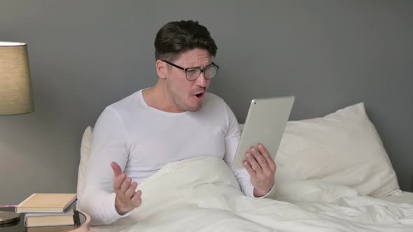 Middle Aged Man Reacting to Loss on Tablet in Bed