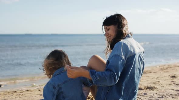 Mother and Daughter Sitting on the Sand Spending They Time Together at Summer Sea. Back View. Happy