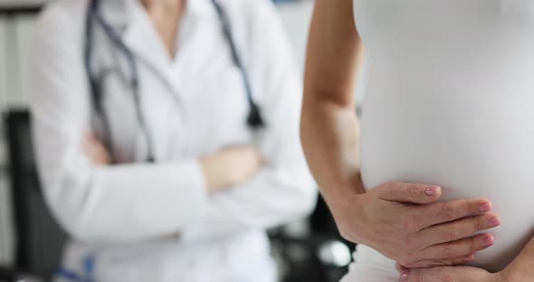 Pregnant Woman Strokes Belly at Gynecologist Appointment