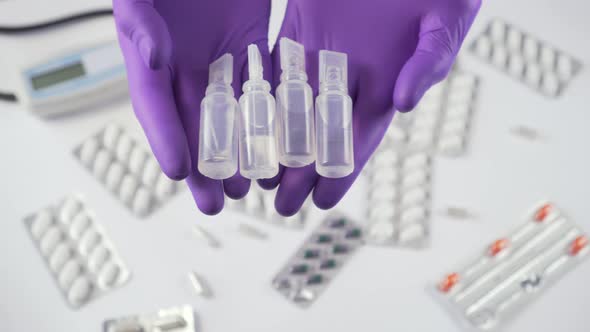 Four plastic medical ampoules in hands in protective gloves 