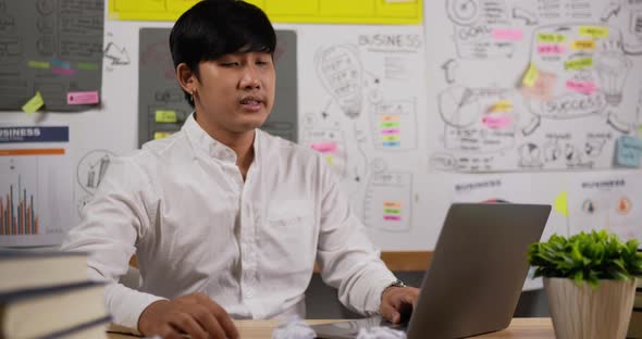 Serious Asian businessman working on laptop in the workplace