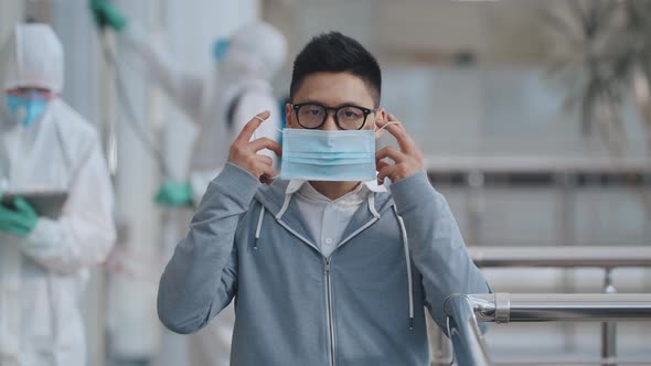 Covid-19 Coronavirus Outbreak. Spreading Prevention. Asian Man Putting Face Mask in Public Place