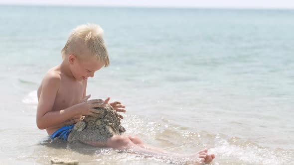 Little Blonde Boy Playing with Sand on Beach Ocean Sea