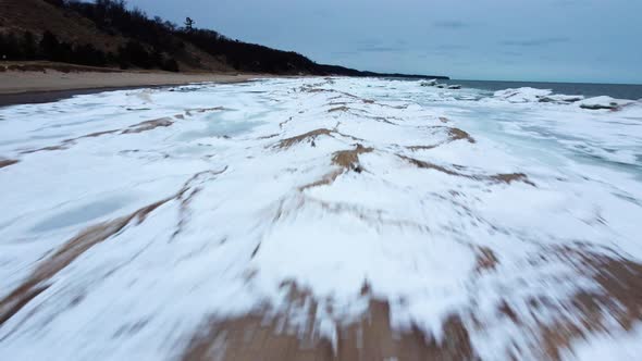 4K drone shot of frozen shoreline with sand dunes