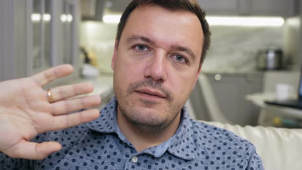 Male Sitting on Sofa at Home and Saying Goodbye to Colleagues Finishing Live Video Conference