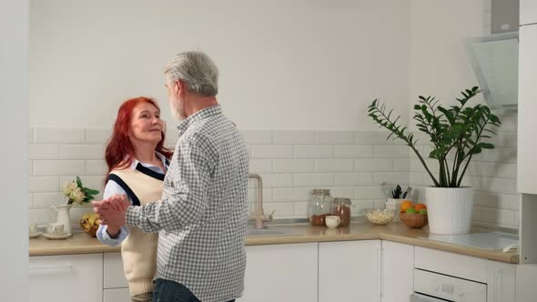 Loving Senior Couple 6070 Years Old Slow Dance at Home in the Kitchen