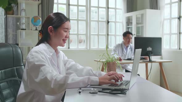 Young Asian Woman Doctor Is Using Laptop In Workplace. Medical Concept