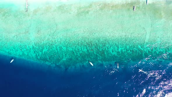 Daytime drone tourism shot of a sandy white paradise beach and blue sea background in colourful 4K