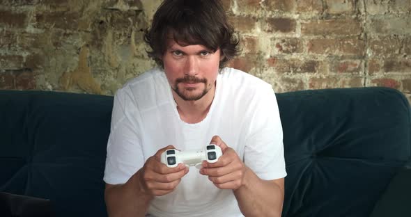 A Male Freelancer Spending His Work Time Playing Video Games While Sitting on a Coach