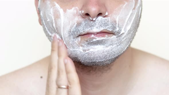 bearded man is applying shaving foam on face. skincare cosmetology concept.morning routine.bottom