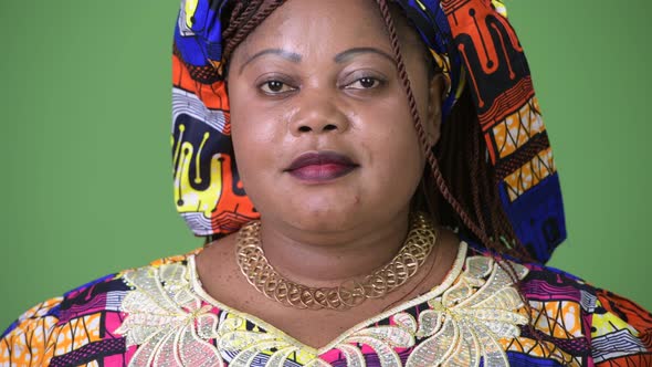 Overweight Beautiful African Woman Wearing Traditional Clothing Against Green Background