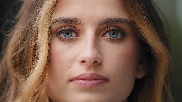 Extreme Closeup Female Young Face with Perfect Skin Blue Eyes Looking at Camera Often Blinks Feels