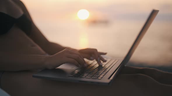A Female Freelancer is Working on Laptop Near Sea
