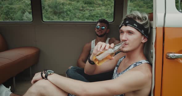 Two Guys Sitting Inside of a Retro Van One Drinking