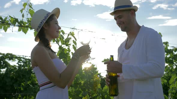 Happy Farmer Treats Rural Girl with Wine of Autumn Harvest and Flirts on Vineyard Plantation in