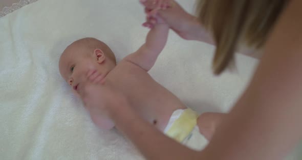 Mother Training Exercises with Newborn Baby on Bed