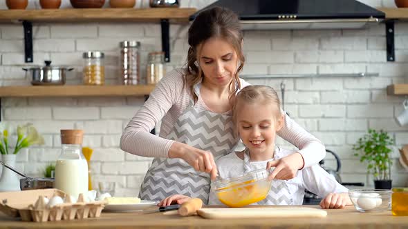 Mother and little, cuta daughter preparing food together.