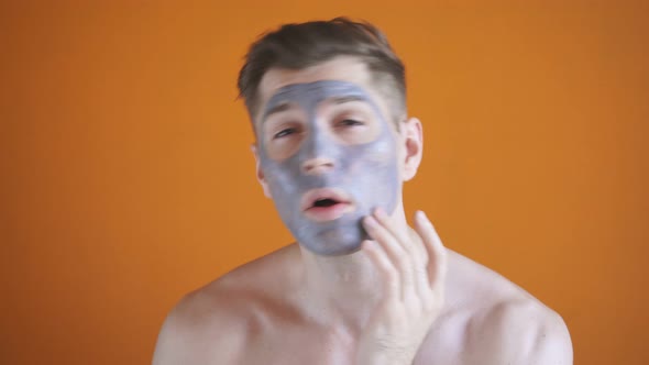 Caucasian Young Guy Shirtless with Cosmetic Gray Clay Mask on His Face, Man Wants To Get Healthy
