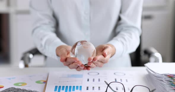 Businesswoman Holds Glass Globe at Workplace
