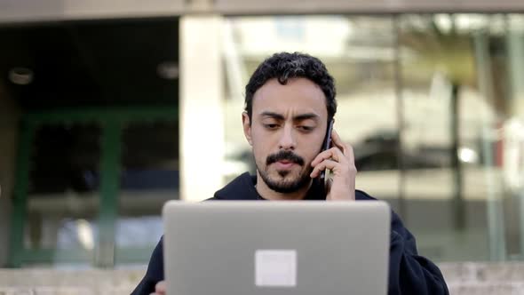 Focused Man Using Laptop and Smartphone