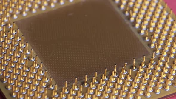 The Old Computer Processor CPU with Gold Plated Contacts Spins on Red Background