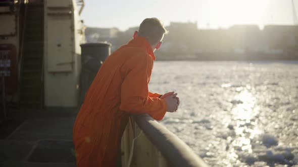 Young Man in Orange Uniform Traveling on Board of the Ship in Winter