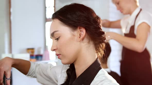 Portrait of hairstylist combing client hair