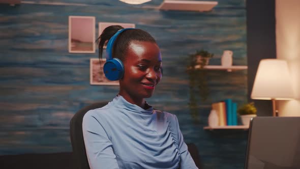 African Lady Listening Music in Wireless Headphones Working Overtime