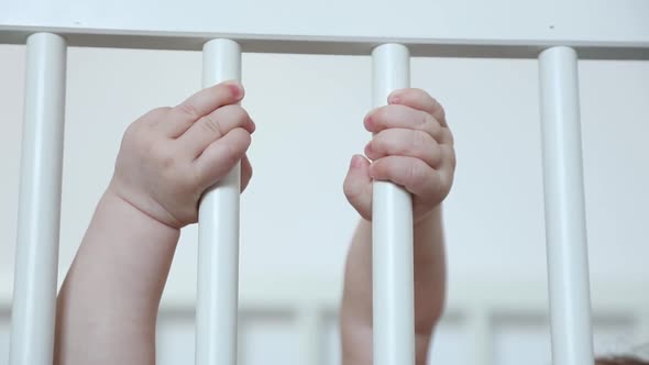 little baby boy hands touching on the railing in the bed