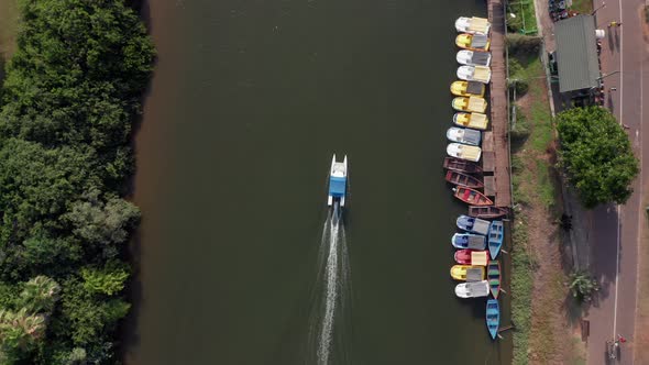 Small White boat heading upstream of the Yarkon river passing under city bridges.