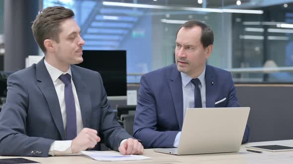 Businessman and Colleague Reacting to Loss While Using Laptop