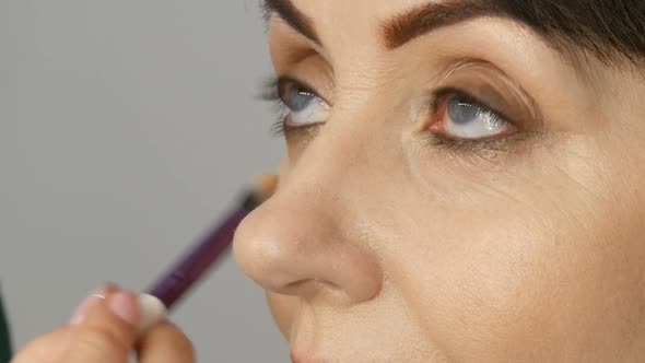 Make Up Artist Do Eye Makeup to Middleaged Woman with Blue Eyes