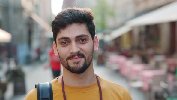 Portrait of Smiling Indian Man with Backpack Posing Outdoors