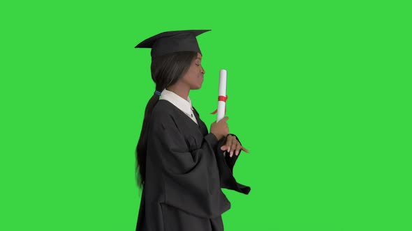 Happy African American Female Graduate Dancing with Her Diploma on a Green Screen, Chroma Key.