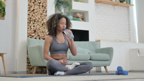 Tired African Woman Drinking Water While Doing Yoga at Home