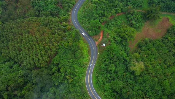 Aerial view over a winding road in the mountains of a tropical forest, Thailand.