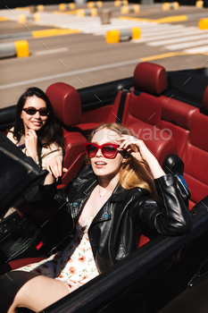 amera driving cabriolet car with smiling friend near on city streets outdoor